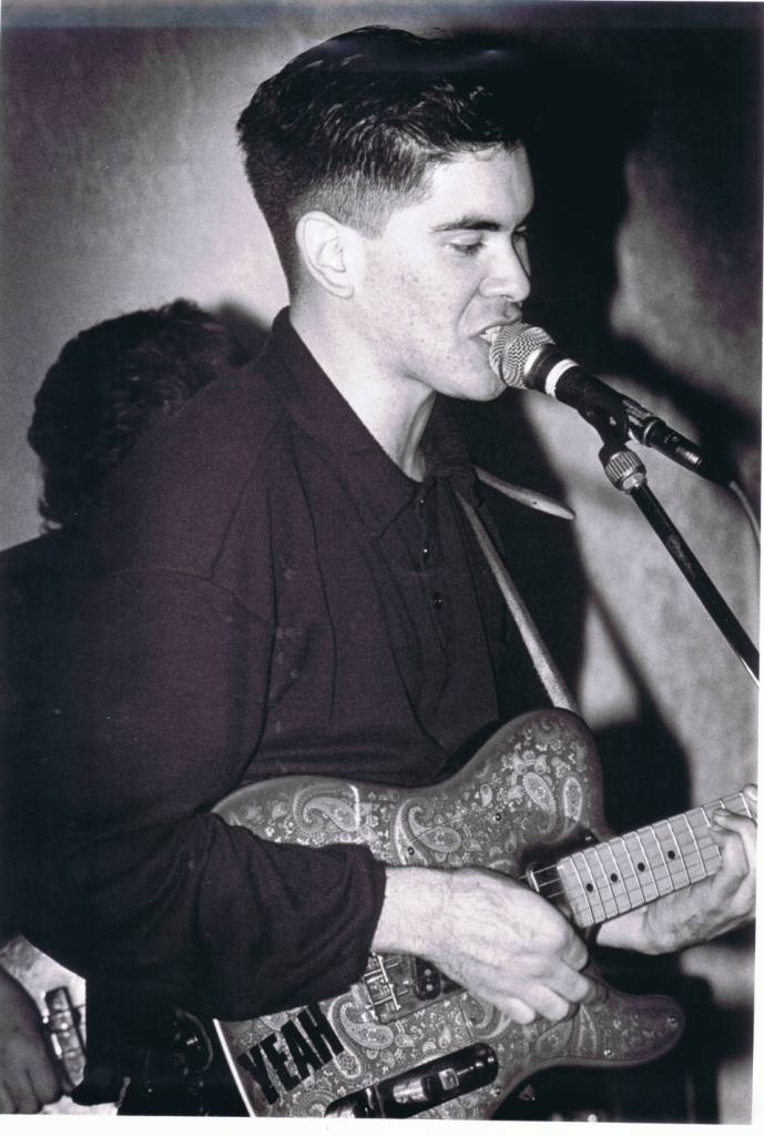 A person holding a guitar

Description automatically generated